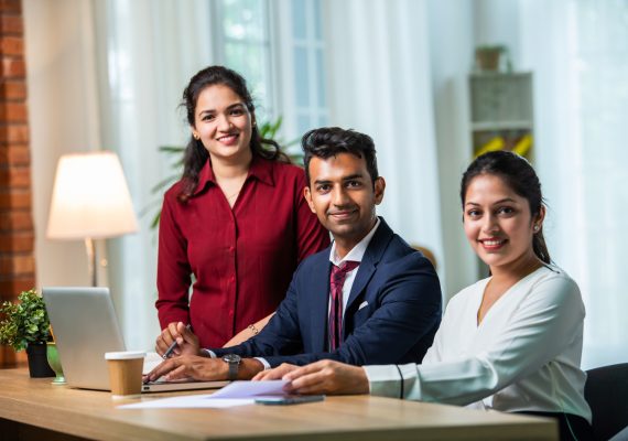 Indian young businesspeople using laptop in group meeting at desk